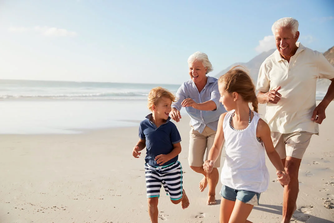 Grandparents running on the beach with their grandchildren